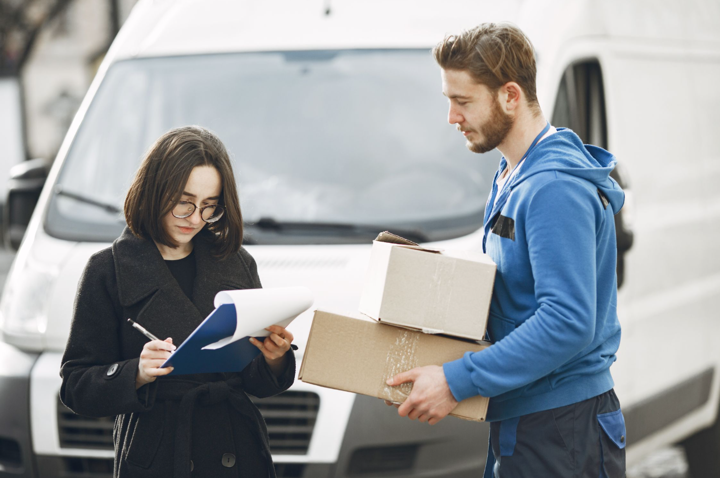 Courier and a clerk checking a parcel by a delivery van